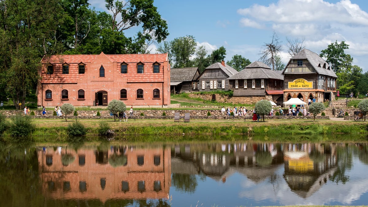 Explore quaint village life with reflections of traditional architecture along a serene river.