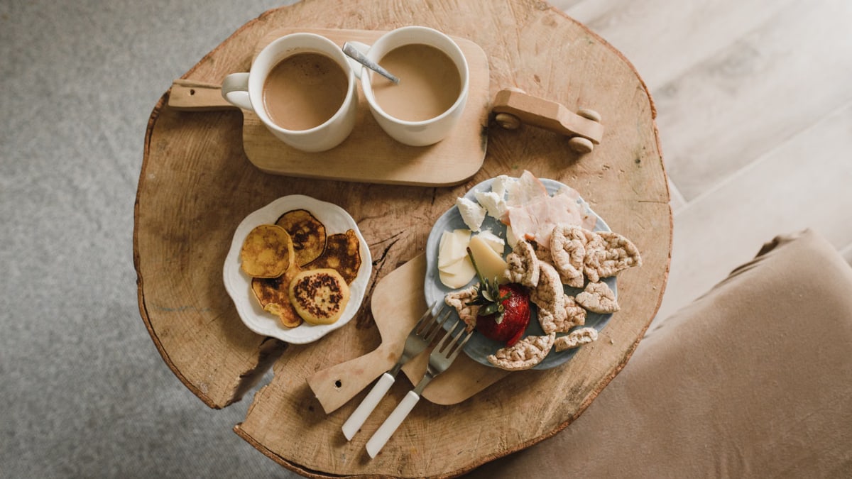 Top view of pancakes and coffee on a rustic wood table, creating a warm breakfast setting.